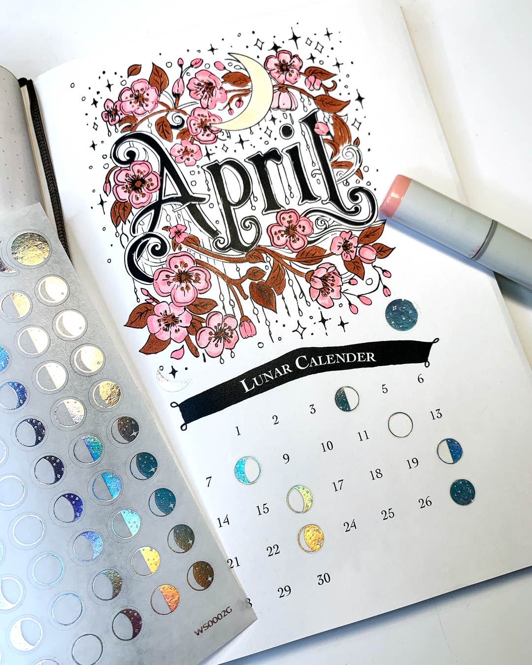 Moon Phase Washi Stickers in holo foil integrated into a handmade April journaling calendar spread, showing lunar phases marked with small 8mm holo foil stickers on a decorated planner page.