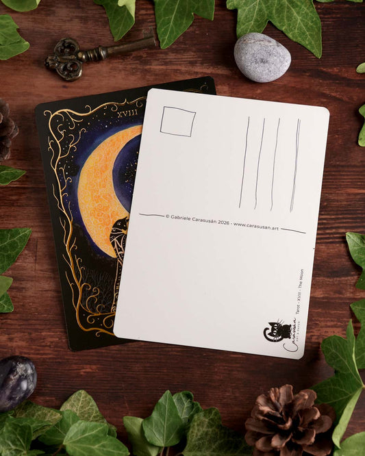Front and back of the "The Moon" Tarot postcard featuring gold foil details and a classic postcard back, styled on a wooden table with ivy.